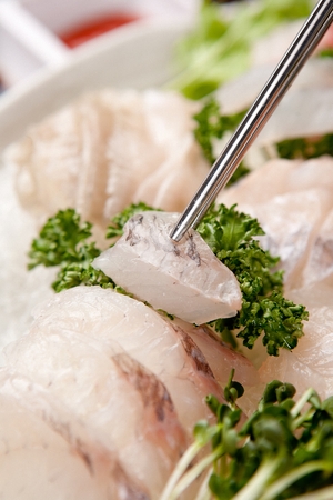Chopsticks grabbing Sea bream sashimi, raw sea bream sliced thinlyの写真素材