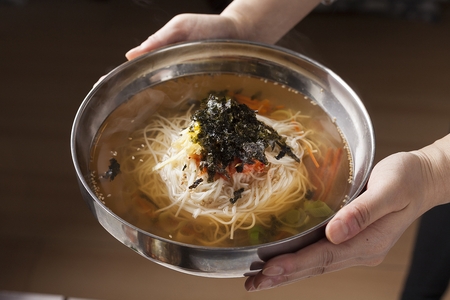 Myeolchi guksu, korean noodles with hot anchovy broth with vegetables and seaweed power, on silver plateの写真素材