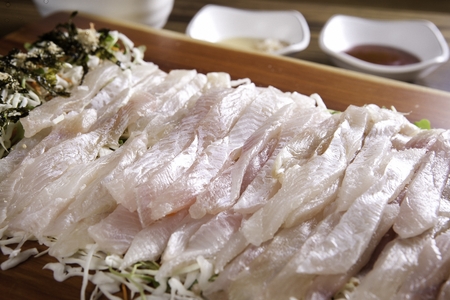 Flatfish sashimi, raw flatfish sliced thinly, on wooden cutting boardの写真素材