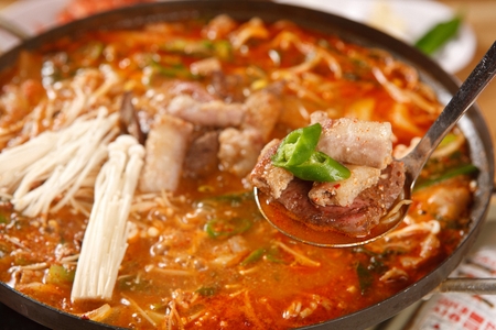 Ladle with gopchang jeongol, a spicy Korean cuisine, vegetables and tripes boiled in a black potの写真素材