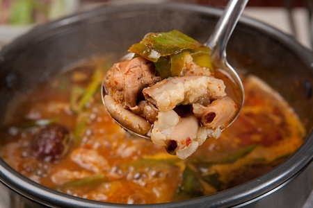 Ladle with gopchang jeongol, a spicy Korean cuisine, vegetables and tripes boiled in a black potの写真素材
