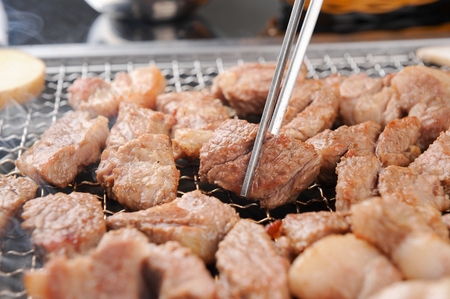 Chopsticks grabbing grilled pork neck sliceの写真素材