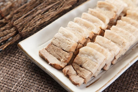 Bossam, a Korean cuisine, boiled pork, on a square white plateの写真素材