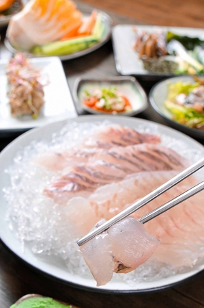 Chopsticks grabbing Rockfish sashimi, raw rockfish sliced thinlyの写真素材