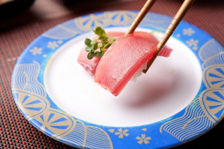 Chopsticks grabbing tuna sushi, on a round plateの写真素材