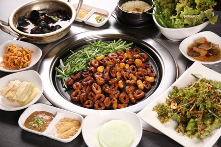 Marinated pork makchang, chives, side dishes being grilled on a black grillの写真素材