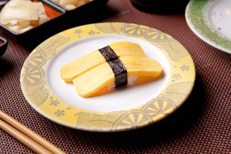 Two pieces of egg sushi, on a round plateの写真素材