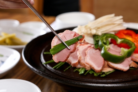 Smoked duck, paprika, enoki mushrooms, being grilled, on a black grillの写真素材