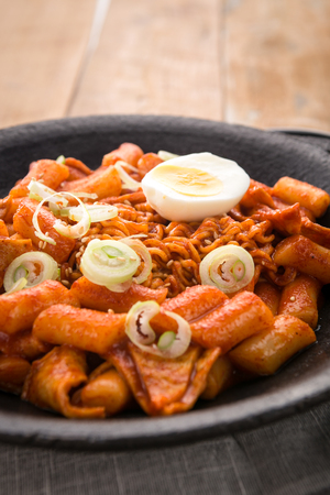 Tteokboki, a Korean cuisine, rice cake and fish cakes stir-fried with spicy sauce, with boiled egg, in a black potの写真素材