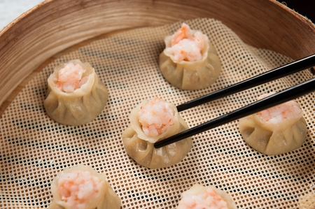 Chopsticks grabbing shrimp Xiaomi, a Chinese cuisine, in a wooden steamerの写真素材