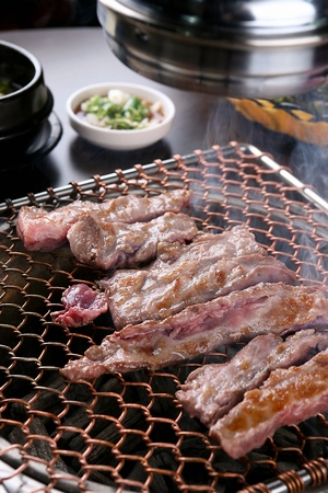 Pork skirtmeat, being grilled, on a grill placed over charcoalの写真素材