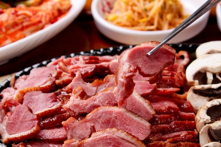 Chopsticks grabbing smoked duck, on a black plateの写真素材
