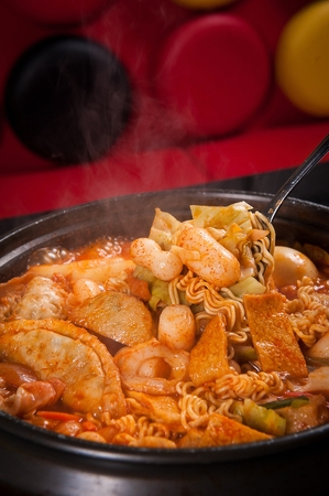 Spoon lifting tteokbokki, stir-fried with fish cakes and vegetables and fries in brothの写真素材