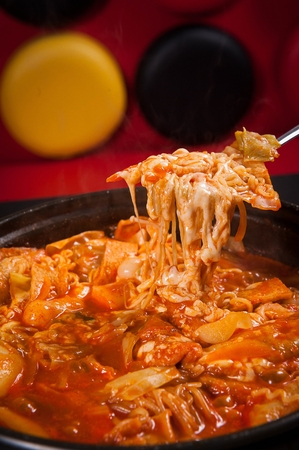 Spoon lifting tteokboki, a Korean cuisine, rice cake and fish cakes stir-fried with spicy sauce, boiled in a potの写真素材