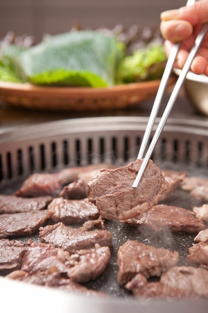 Chopsticks grabbing beef sirloin, being grilledの写真素材