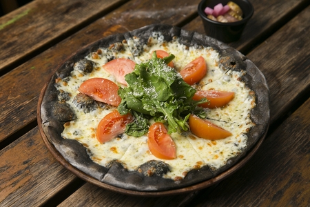 Salad pizza with tomatoes and vegetables, made of black doughの写真素材