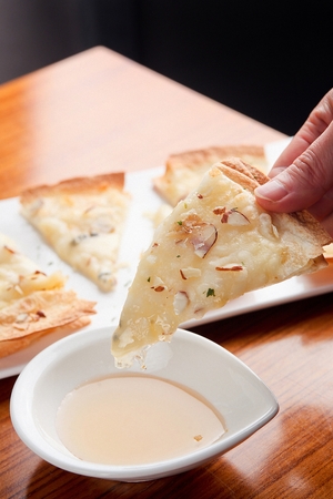 Gorgonzola pizza with sprinkled almonds, dipped in honey
