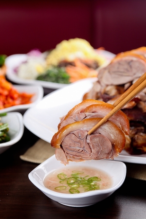 Chopsticks picking up jokbal, thinly sliced boiled pork feet and dipping it in sauceの写真素材