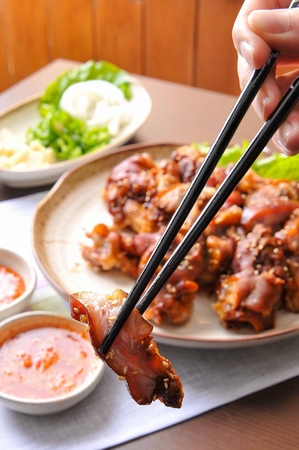 Chopsticks picking up jokbal, thinly sliced boiled pork feet and dipping it in sauceの写真素材