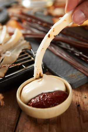Squid being dipped in mayonnaise and red pepper paste