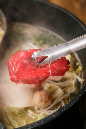 Thin beef going in a hotpot with boiling vegetablesの写真素材
