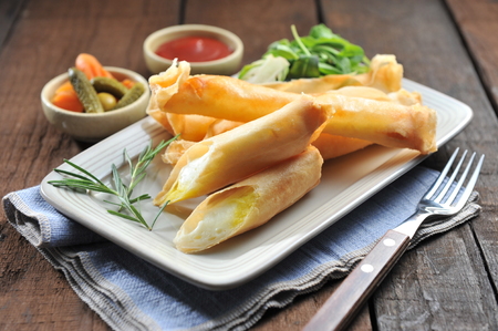 Cheese sticks, long cheese fried with bread crumbs, with pickles, ketchip and fork