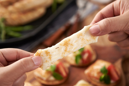 Hands pulling baked cheese