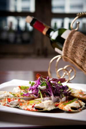 Grilled cheese oysters, with finely chopped vegetables, on white plateの写真素材