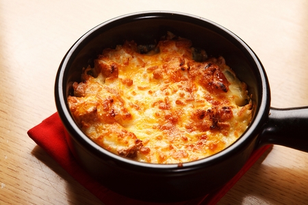 Cheese gratin in black oven plate, close-up