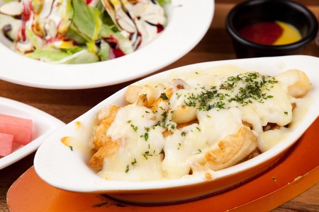 Cheese gratin, lots of cheese on french fries, on white oven plate