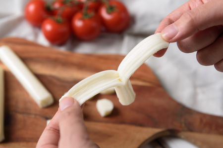 Hand pulling string cheese on wooden treyの写真素材