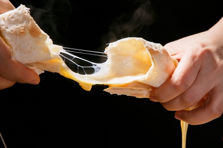Cheese bread being pulled with hands, showing cheese