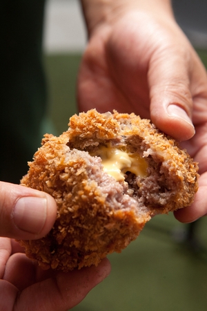 Hand pulling cheese mince cutlet, which has cheddar cheese