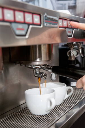 Barista dripping espresso coffee in white coffee mugの写真素材