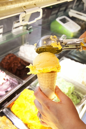 Mango ice cream being scouped on an ice cream cone