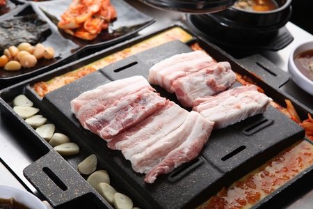 Meat and garlic on grill, with side dishesの写真素材