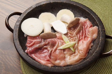 Lamb and beef intestines, onions, mushrooms being grilled on black stone tabletsの写真素材