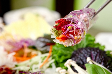 Chopsticks picking up Vietnamese spring rolls, made of rice paper, vegetables, shrimps etc.の写真素材
