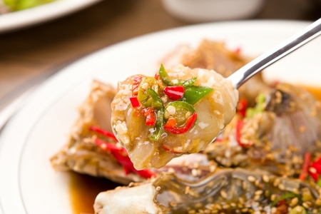 Spoon scooping up soy sauce marinated crab with sprinkled perilla seeds and chiliの写真素材