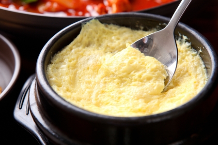 Spoon scooping up steamed egg, from black potの写真素材