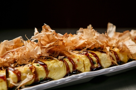 Teriyaki sauce on Rolled omelet with minced vegetables, on white plate