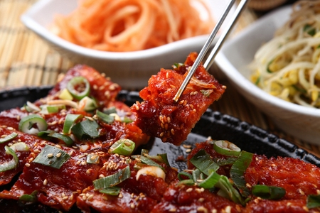 Chopsticks picking up grilled dried pollacks with spicy sauceの写真素材
