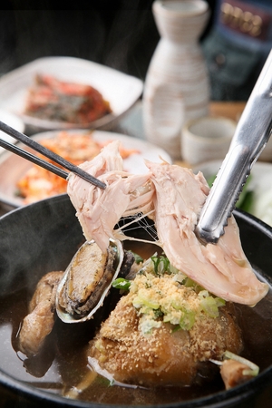 Whole chicken soup in pot, on tableの写真素材