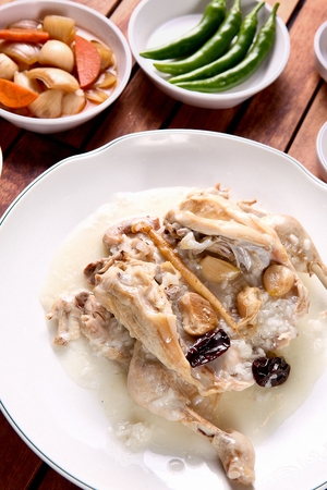 Dak-baeksuk, korean style chicken soup dish with a whole chicken and vegetables, in white bowl
