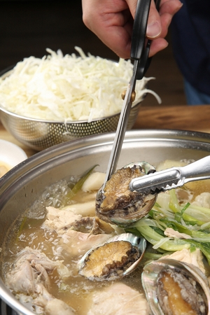 Abalones whole chicken soup boiling in potの写真素材