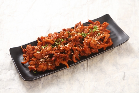 Boneless chicken feet marinated in spicy sauce, on black plateの写真素材