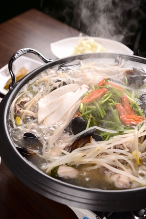 Clear broth soup with seafood, chicken and bean sprouts, in potの写真素材