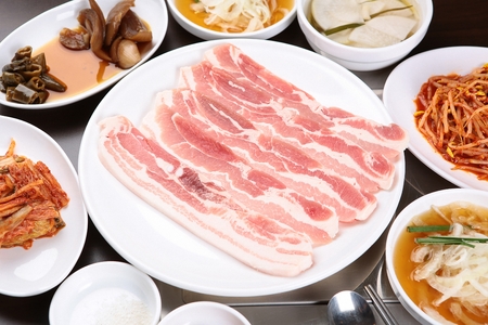Raw pork belly and side dishes on white plateの写真素材