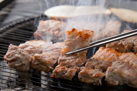 Chopsticks picking up pork belly with cuts, from charcoal grillの写真素材