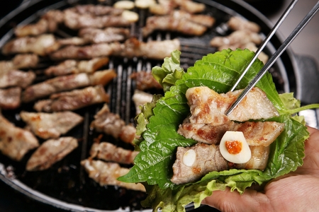 Grilled pork, garlic and soybean paste on lettuce and perilla leafの写真素材